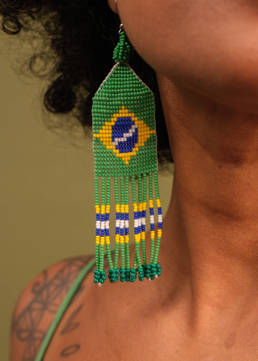 Brinco de miçangas verde, amarelo e azul feito pelo povo Waurá, artesanato indígena brasileiro 