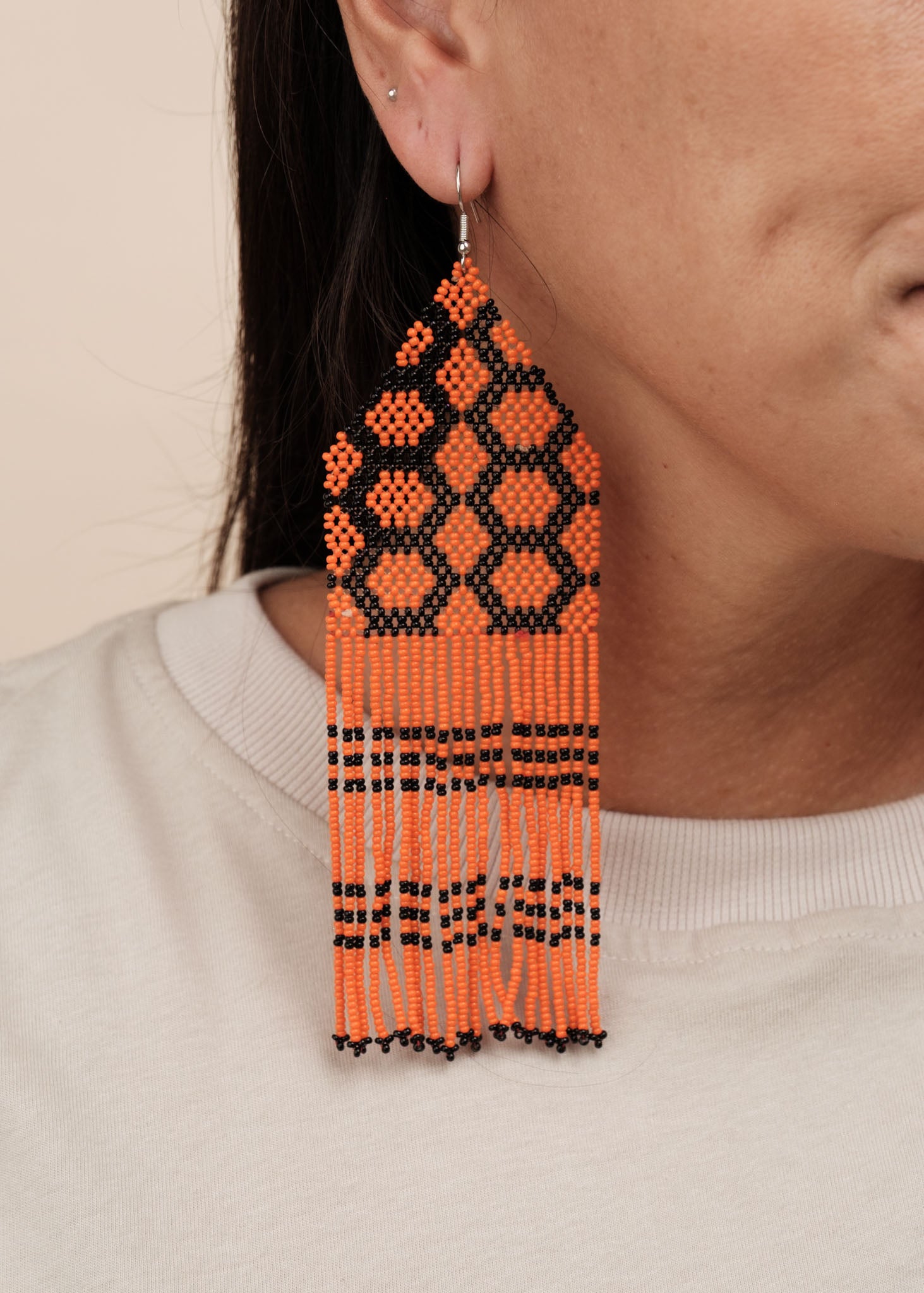 Brincos de miçangas laranja e preto feitos pelo povo Kayapó, artesanato indígena brasileiro 