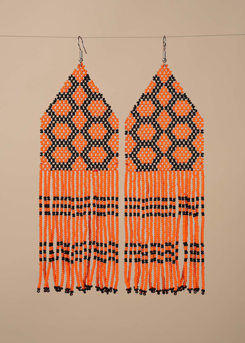 Brincos de miçangas laranja e preto feitos pelo povo Kayapó, artesanato indígena brasileiro 