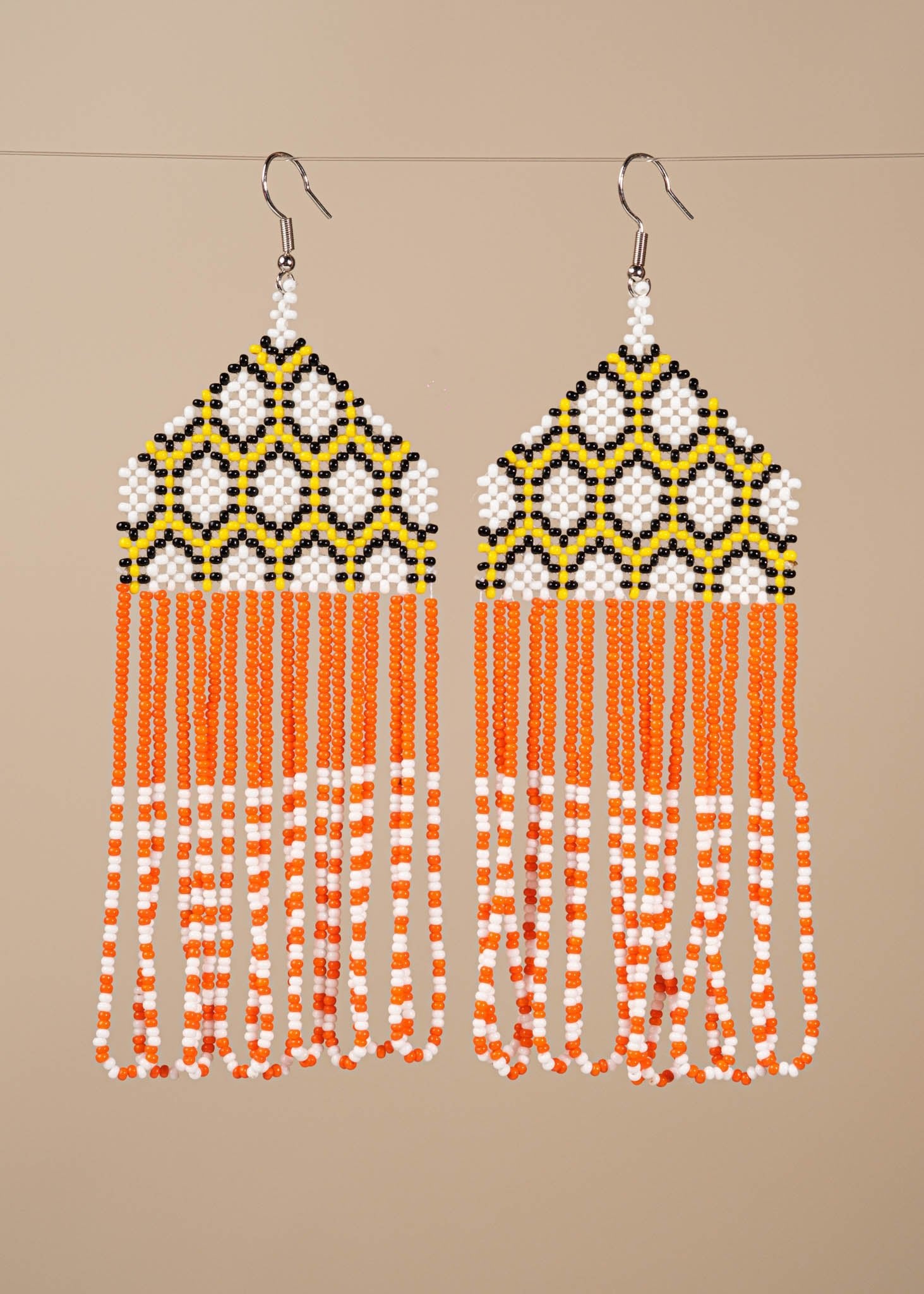 Brincos de miçangas laranja, branco e amarelo feitos pelo povo Kayapó, artesanato indígena brasileiro 