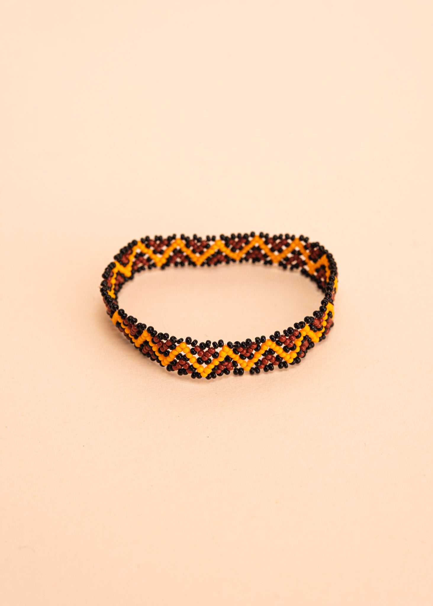 Pulseira de miçangas amarela e marrom feita pelo povo Waurá, artesanato indígena brasileiro