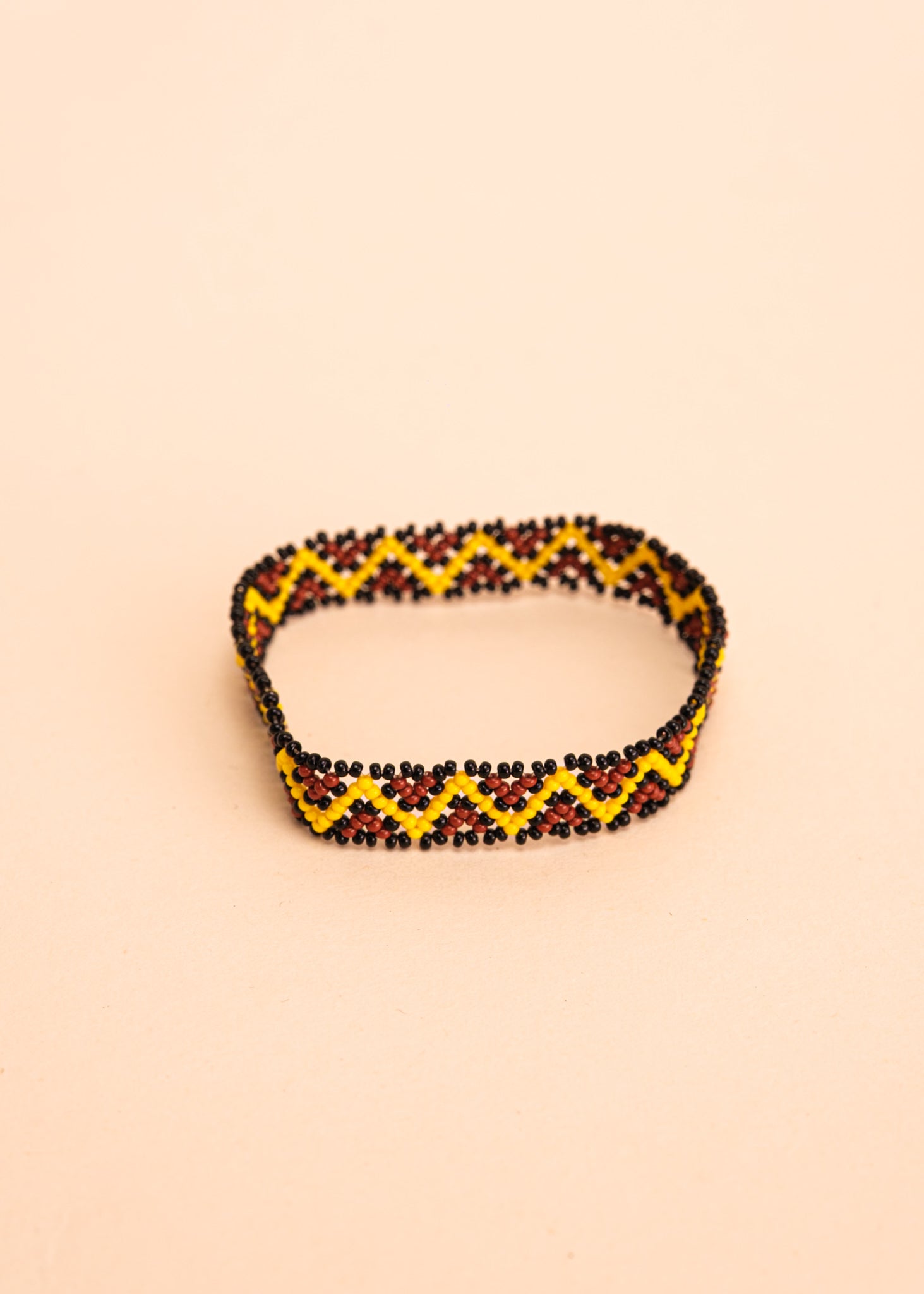 Pulseira de miçangas amarela e marrom feita pelo povo Waurá, artesanato indígena brasileiro